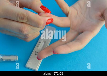 test sanguin pour le diagnostic du coronavirus. la jeune fille s'est crevée le doigt pour elle-même et a pressé le sang du doigt. échantillon de sang capillaire Banque D'Images