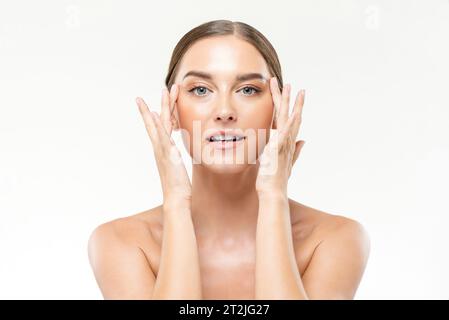 Soins de la peau portirait de belle femme caucasienne massant le visage avec les mains sur fond blanc dans le studio de lumière Banque D'Images