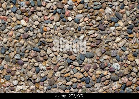 Fond de macro texture abstraite plein cadre d'une vieille surface de marche agrégée avec des pierres exposées et des cailloux en plein soleil Banque D'Images