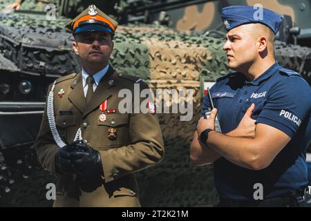 16.08.2023 Varsovie, Pologne. Portrait en plein air d'un soldat et policier polonais debout devant un véhicule militaire recouvert de peinture camouflage. Photo de haute qualité Banque D'Images