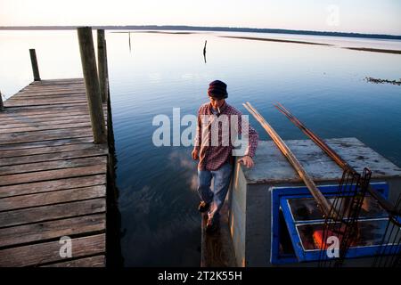 Un jeune homme fume sa cigarette avant de prendre son bateau fait maison pour les lits d'huîtres tôt un matin à Apalachicola Bay, en Floride. Banque D'Images