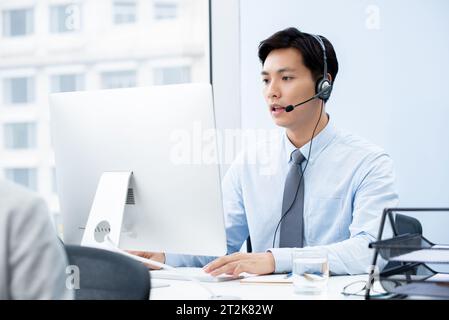 Opérateur de télémarketing homme asiatique travaillant dans le bureau du centre d'appels Banque D'Images