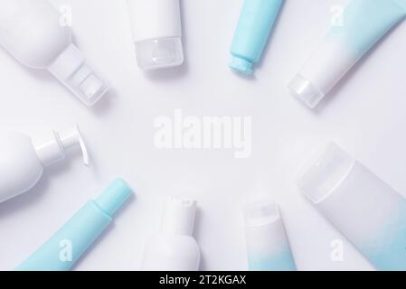 Bouteilles et tubes avec des produits cosmétiques sur un fond bleu doux Banque D'Images