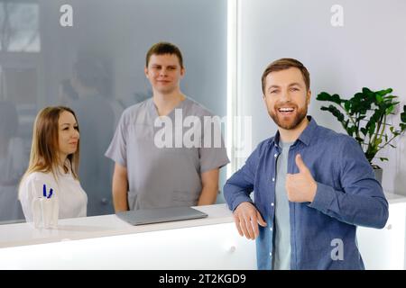 Patient reconnaissant. Homme debout à la réception de la clinique dentaire et très heureux pour le traitement Banque D'Images