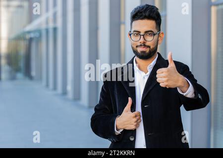 J'aime. Heureux homme d'affaires indien soulève les pouces vers le haut accepte donne une réponse positive recommande la publicité aime la rétroaction de bonne idée, célébrant la victoire de succès. Arabian Hindu freelance gars dans la rue de la ville Banque D'Images