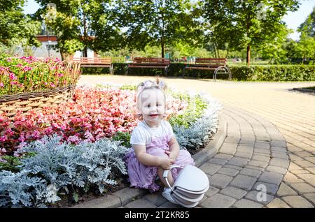 Élégante petite fille se détendre dans le parc de la ville d'été. Adorable petite fille passer un bon moment. Enfance Banque D'Images