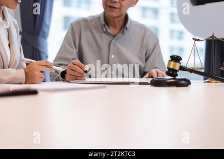 Avocat principal expliquant l'accord juridique avec la femme d'affaires et pointant sur le contrat pour la signature. Banque D'Images