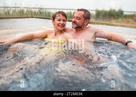 Un couple marié heureux profiter du temps passé le week-end dans la piscine. Un homme et une femme sont assis dans l'eau bouillonnante. Les jeunes prennent un jacuz Banque D'Images