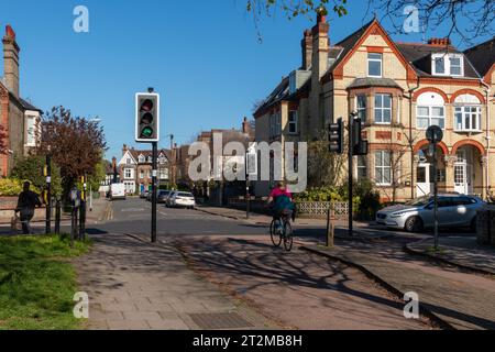 Un cycliste, obéissant à la loi, passant par un carrefour de piste cyclable lorsque le feu vert spécifique au vélo apparaît. Cambridge, Royaume-Uni Banque D'Images