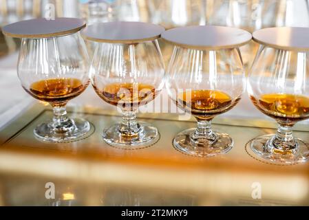 Gros plan des verres à boire transparents couverts de rangée avec du rhum sur les sets de table de dégustation. Événement pour les connaisseurs de liqueurs anciennes mélangées Banque D'Images