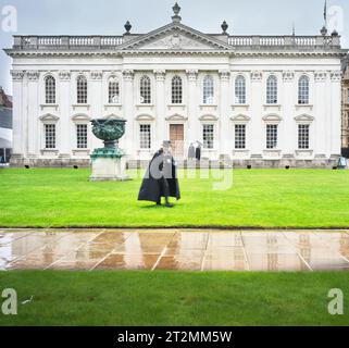 Un jour pluvieux à Senate House, Université de Cambridge, Angleterre, en tant que gardien avec un chapeau haut de gamme course sur la pelouse du Sénat avant la cérémonie de remise des diplômes le 20 octobre 2023 Banque D'Images