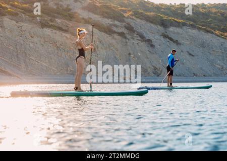06 août 2023. Budva, Monténégro. Couple aviron sur stand up paddle board à la mer tranquille. Banque D'Images