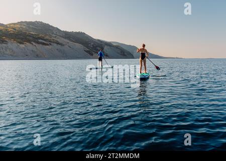 06 août 2023. Budva, Monténégro. Couple ramant sur stand up paddle board. Vacances d'été sur Red paddle SUP board dans la mer calme. Banque D'Images