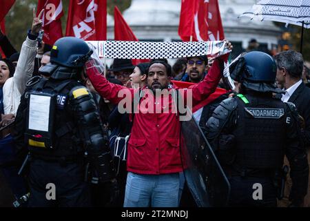Un manifestant tient un foulard devant la police pendant la manifestation pro-Palestine. Des milliers de personnes se sont rassemblées à nouveau sur la place de la République à Paris pour manifester leur soutien au peuple palestinien et exiger un cessez-le-feu immédiat des forces israéliennes. Bien que le ministre de l’intérieur Gérald Darmanin maintienne sa position sur l’interdiction de toutes les manifestations pro-palestiniennes, le Tribunal administratif de Paris a annulé cette décision, autorisant cette manifestation pour une heure seulement, de 7h à 8H. Banque D'Images