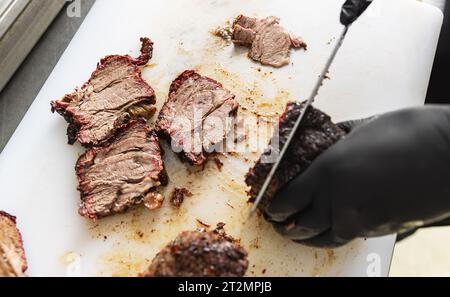 Mains du chef trancher le steak de bœuf avec un couteau. Concept de processus de préparation des aliments. Banque D'Images