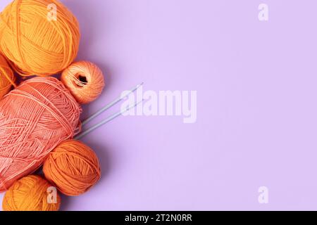 Mise en page créative faite de fils orange et rose pour tricoter sur un fond lilas avec place pour votre texte. Tricot à l'aiguille de loisir. Concept faites-le Banque D'Images