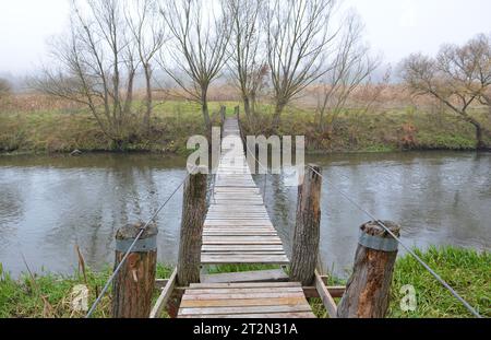 Un pont en bois traversant une petite rivière Banque D'Images