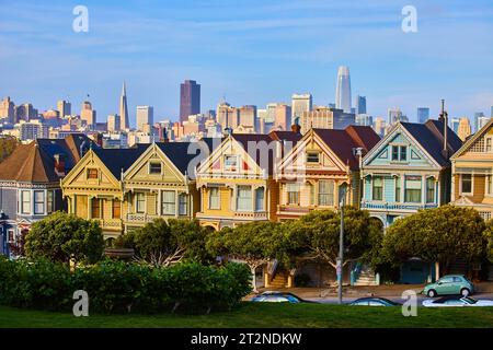 Rangée des Painted Ladies au coucher du soleil avec lueur dorée sur la ville de San Francisco en arrière-plan Banque D'Images