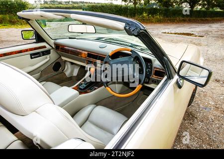 Cockpit d'une Jaguar XJS décapotable avec top down sur un parking en gravier dans le pays Banque D'Images