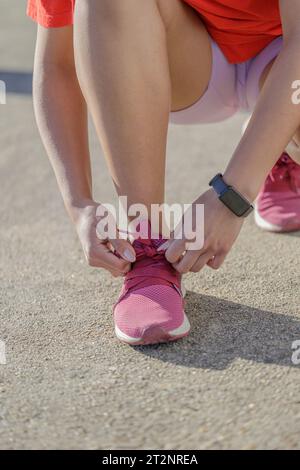 Gros plan d'une fille nouant ses lacets de chaussures. Banque D'Images