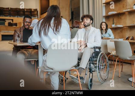Portrait de l'homme moderne à l'aide d'un ordinateur portable au bureau moderne. Une personne handicapée en fauteuil roulant travaille au bureau Banque D'Images