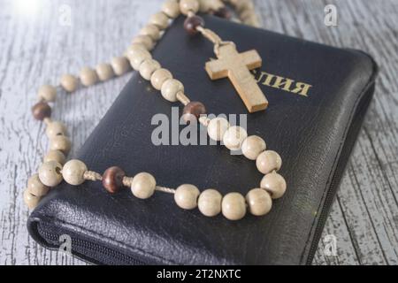 Zoomez sur un Rosaire en bois au-dessus d'un livre ouvert parmi de petites bougies sur une table blanche Banque D'Images