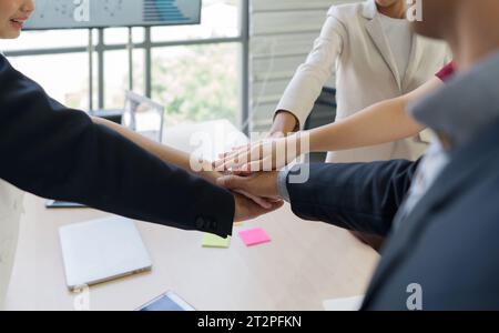 Les professionnels d'entreprise engagés dans l'entreprise unissent leurs mains pour marquer la collaboration, dans un environnement de bureau moderne. Banque D'Images