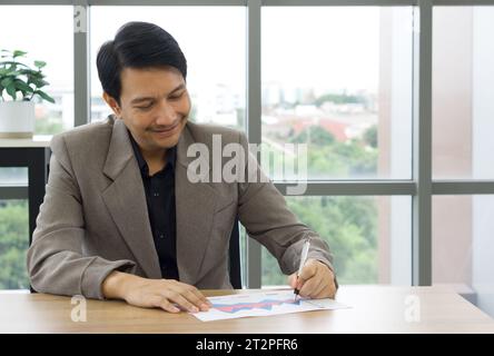 Homme d'affaires productif et concentré écrivant diligemment sur un morceau de papier à son bureau dans un cadre professionnel. Banque D'Images