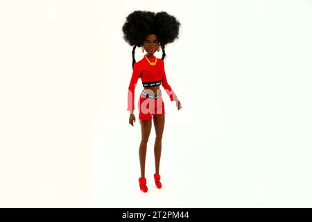 9 octobre 2023. Barnaul, Russie : poupée Barbie afro-américaine avec les cheveux noirs dans un costume rouge debout isolé sur un fond blanc. Banque D'Images