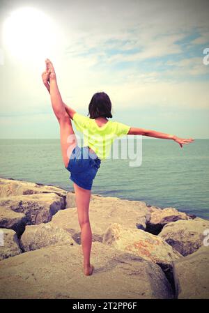 jeune fille de derrière avec sa jambe vers le haut faisant de la gymnastique et effet de tons antiques Banque D'Images