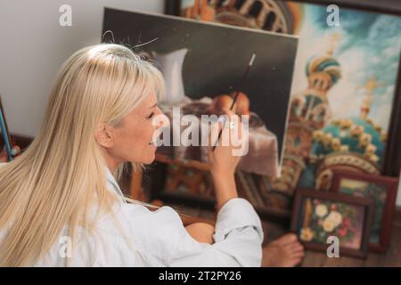 Jeune femme peintre blonde dans son atelier Banque D'Images