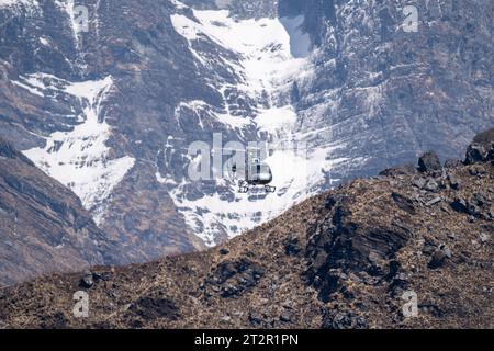 Un hélicoptère écumant au-dessus d'une crête de montagne dans les montagnes de l'Himalaya au Népal. Banque D'Images