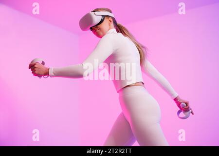 Femme dans l'entraînement de lunettes de VR par fond éclairé Banque D'Images