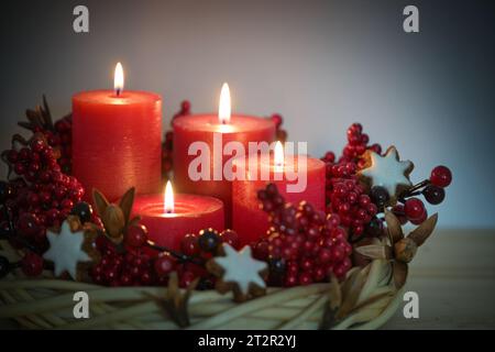 Couronne de l'AVENT en osier de saule avec quatre bougies rouges allumées, biscuits étoilés à la cannelle et baies, décoration de vacances pour Noël, espace de copie, Banque D'Images