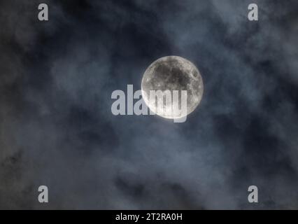 Une pleine lune qui brille parmi les nuages dans le ciel nocturne au-dessus du Canada Banque D'Images