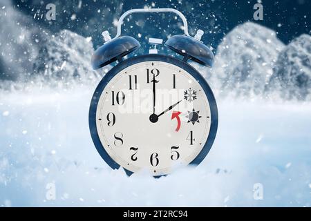 21 October 2023: Time change from summer time to winter time. An alarm clock covered with snow in a winter landscape and a sun and ice symbol for 2 and 3 o clock. Set clock back concept PHOTO MONTAGE *** Zeitumstellung von Sommerzeit auf Winterzeit. Ein mit Schnee bedeckter Wecker in einer Winterlandschaft und einer Sonne und einem Eis Symbol für 2 und 3 Uhr. Uhr zurückstellen Konzept FOTOMONTAGE Credit: Imago/Alamy Live News Banque D'Images