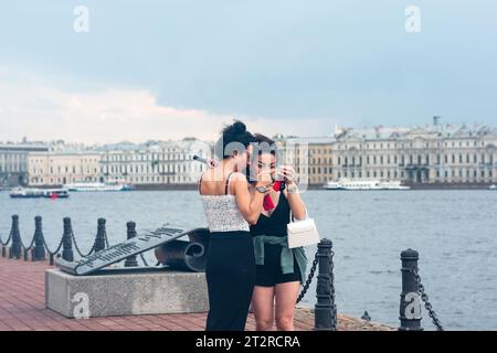 Saint-Pétersbourg, Russie - 02 août 2023 : femmes touristes sur le remblai regardant des photos prises sur un smartphone Banque D'Images