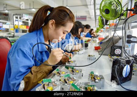 Fuyang, Chine. 18 octobre 2023. Les femmes portant des combinaisons bleues travaillent sur la chaîne de montage d'une usine qui produit du matériel électrique. Le produit intérieur brut de la Chine a augmenté de 4,9 pour cent en glissement annuel au troisième trimestre, après une hausse de 6,3 pour cent au deuxième trimestre, affichant une reprise régulière malgré les pressions à la baisse, a déclaré mercredi le Bureau national des statistiques. Au cours des trois premiers trimestres, le PIB de la Chine a augmenté de 5,2 pour cent pour atteindre 91,3 billions de yuans (12,5 billions de dollars), après une croissance de 5,5 pour cent au premier semestre de l'année, a déclaré le bureau. Crédit : SOPA Images Limited/Alamy Live News Banque D'Images