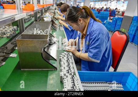 Fuyang, Chine. 18 octobre 2023. Les femmes portant des combinaisons bleues travaillent sur la chaîne de montage d'une usine qui produit du matériel électrique. Le produit intérieur brut de la Chine a augmenté de 4,9 pour cent en glissement annuel au troisième trimestre, après une hausse de 6,3 pour cent au deuxième trimestre, affichant une reprise régulière malgré les pressions à la baisse, a déclaré mercredi le Bureau national des statistiques. Au cours des trois premiers trimestres, le PIB de la Chine a augmenté de 5,2 pour cent pour atteindre 91,3 billions de yuans (12,5 billions de dollars), après une croissance de 5,5 pour cent au premier semestre de l'année, a déclaré le bureau. Crédit : SOPA Images Limited/Alamy Live News Banque D'Images