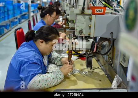 Fuyang, Chine. 18 octobre 2023. Les femmes portant des combinaisons bleues travaillent sur la chaîne de montage d'une usine qui produit du matériel électrique. Le produit intérieur brut de la Chine a augmenté de 4,9 pour cent en glissement annuel au troisième trimestre, après une hausse de 6,3 pour cent au deuxième trimestre, affichant une reprise régulière malgré les pressions à la baisse, a déclaré mercredi le Bureau national des statistiques. Au cours des trois premiers trimestres, le PIB de la Chine a augmenté de 5,2 pour cent pour atteindre 91,3 billions de yuans (12,5 billions de dollars), après une croissance de 5,5 pour cent au premier semestre de l'année, a déclaré le bureau. Crédit : SOPA Images Limited/Alamy Live News Banque D'Images
