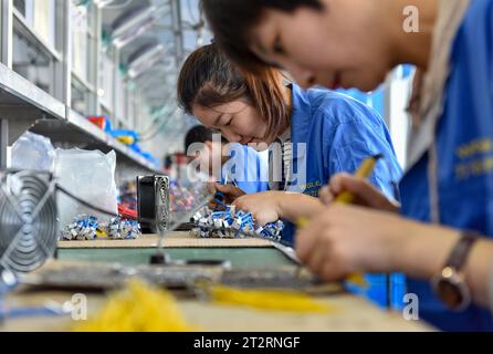 Fuyang, Chine. 18 octobre 2023. Les femmes portant des combinaisons bleues travaillent sur la chaîne de montage d'une usine qui produit du matériel électrique. Le produit intérieur brut de la Chine a augmenté de 4,9 pour cent en glissement annuel au troisième trimestre, après une hausse de 6,3 pour cent au deuxième trimestre, affichant une reprise régulière malgré les pressions à la baisse, a déclaré mercredi le Bureau national des statistiques. Au cours des trois premiers trimestres, le PIB de la Chine a augmenté de 5,2 pour cent pour atteindre 91,3 billions de yuans (12,5 billions de dollars), après une croissance de 5,5 pour cent au premier semestre de l'année, a déclaré le bureau. Crédit : SOPA Images Limited/Alamy Live News Banque D'Images