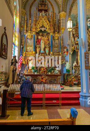 Dyersville, Iowa, États-Unis. Basilique Saint François Xavier, autel de la Sainte mère, érigé en 1897. Adorateur se préparant à allumer une bougie. Vers la gauche o Banque D'Images