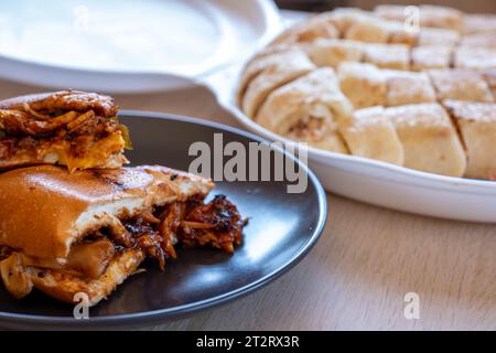 Morceaux italiens de shawarma plein de poivrons et sauces barbecue avec du poulet sur des morceaux de nad shawarma sur une table en bois avec des assiettes noires Banque D'Images