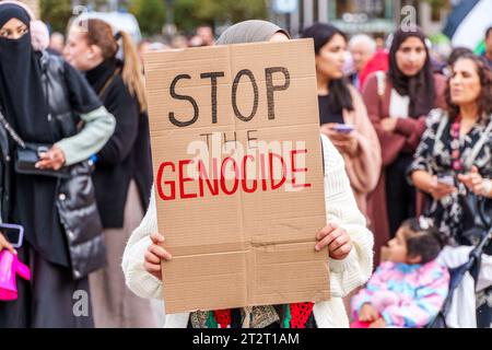 21 octobre 2023, Hesse, Francfort-sur-le-main : un participant tient une affiche "Stop the Genocide". Un rassemblement pro-palestinien sous le slogan "paix et justice au Moyen-Orient" a lieu sur Opernplatz. Le tribunal administratif de Francfort a levé l'interdiction initialement imposée par la ville à la manifestation anti-israélienne. Photo : Andreas Arnold/dpa Banque D'Images