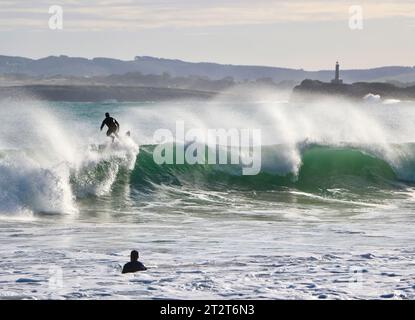 Surfeurs avec l'île de Mouro à l'entrée de la baie avec de fortes vagues sur un matin ensoleillé d'automne Sardinero Santander Cantabria Espagne Banque D'Images