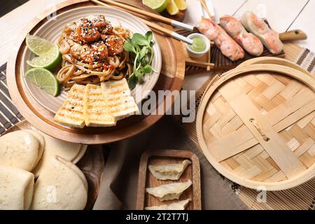 Différents plats chinois sur la table en bois clair, closeup Banque D'Images