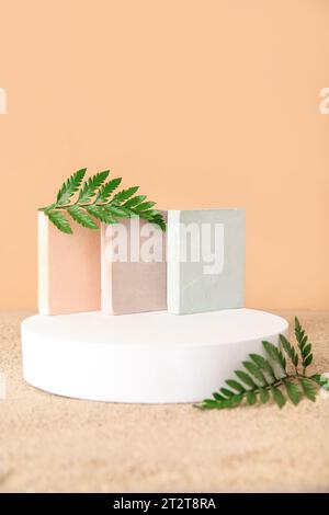 Podiums décoratifs en plâtre avec feuilles de fougères sur fond de sable orange pâle Banque D'Images