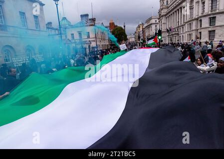 Whitehall, Londres, Royaume-Uni. 21 octobre 2023. Une manifestation est en cours contre l'escalade de l'action militaire à Gaza alors que le conflit entre Israël et le Hamas se poursuit. Organisé par des groupes tels que Palestine Solidarity Campaign et Stop the War Coalition, intitulé « Marche nationale pour la Palestine » et avec des appels à « libérer la Palestine », « mettre fin à la violence » et « mettre fin à l’apartheid ». Grand drapeau de Palestine à Whitehall Banque D'Images