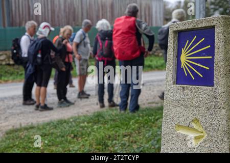 FONSAGRADA, 3 octobre 2023 : pèlerins sur le chemin de Saint-Jacques-de-Compostelle avec une borne de mille du Camino de Santiago Banque D'Images