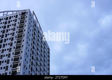 Un bâtiment inachevé se dresse devant un ciel gris sombre, dépourvu de tout signe de vie ou d'activité, avec ses espaces vides qui attendent d'être remplis Banque D'Images